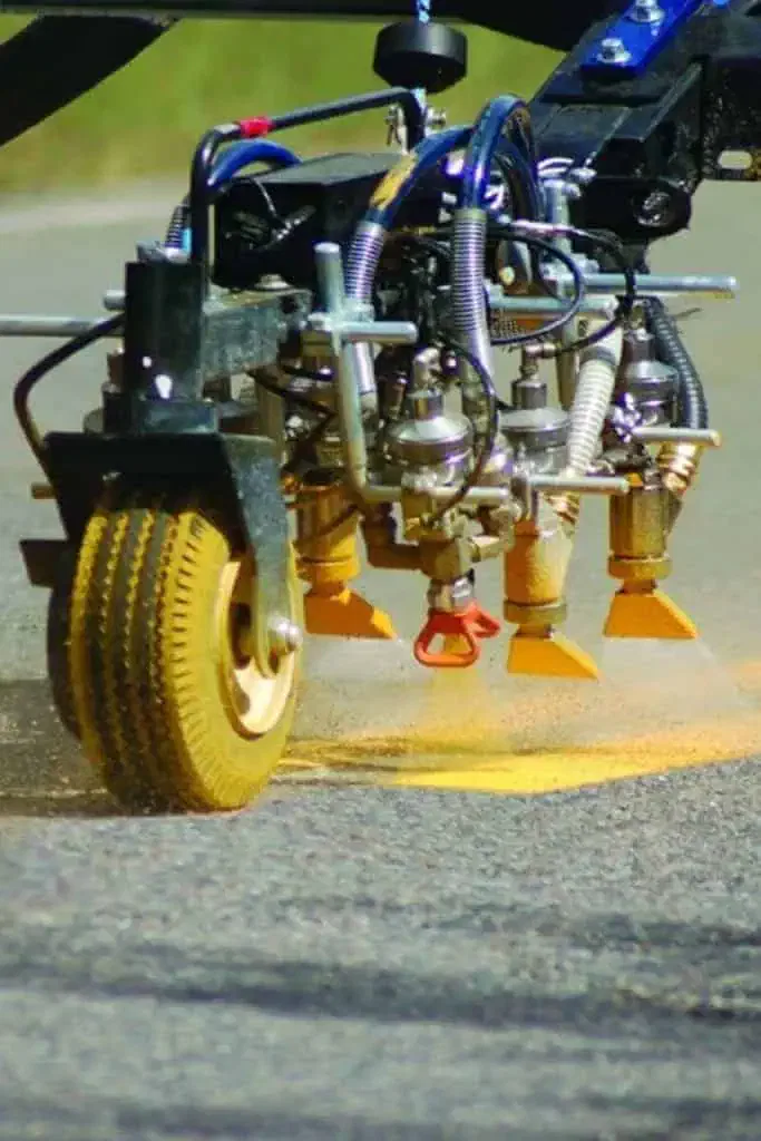 Asphalt driveway paving contractors striping lines on highway with machine